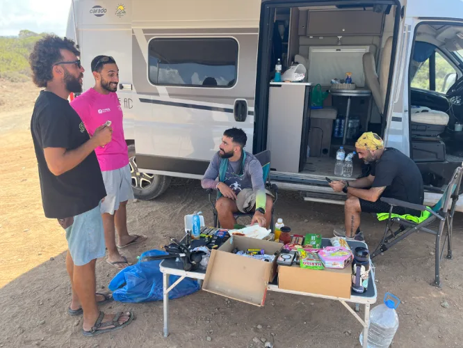 The full crew at a roadside stop, van open, supplies laid out on a table